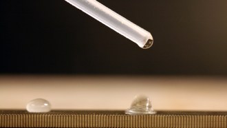 a close up of a pipette droping droplets of water