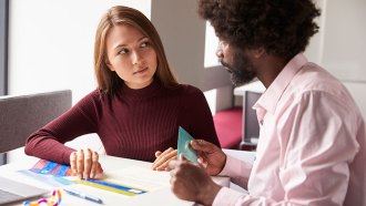 a woman putting colored overlays on a paper as she talks to her teacher