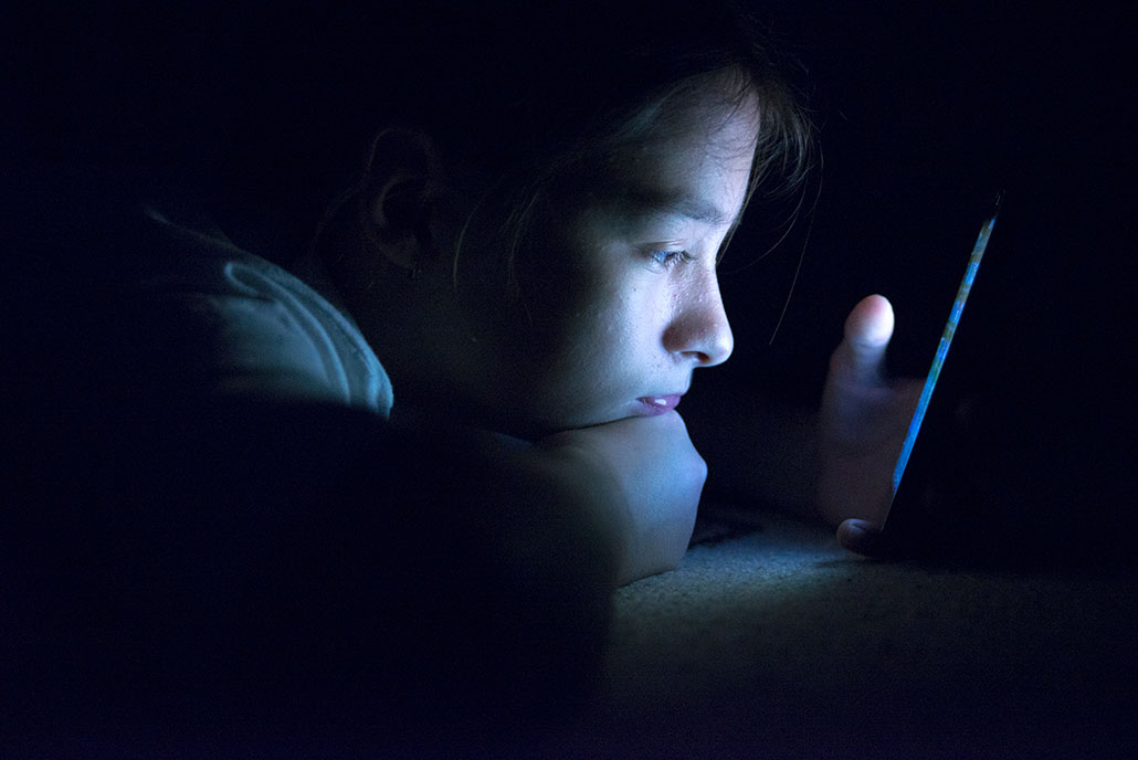 a young kid looking at a screen in a dark room