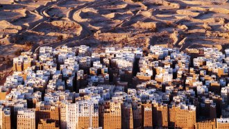 an aerial view of a city with many tall brown and white buildings surrounded by a desert