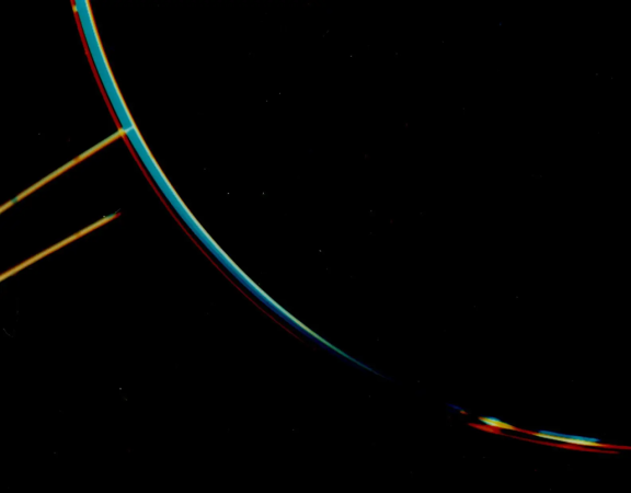 a composite image showing the curve of Jupiter as a line in three colors, and a yellow ring in the top left corner of the picture