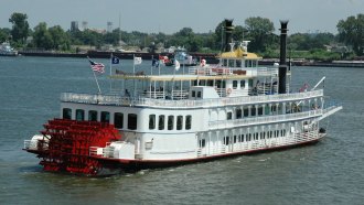 A large white paddleboat on the Mississippi River In New Orleans