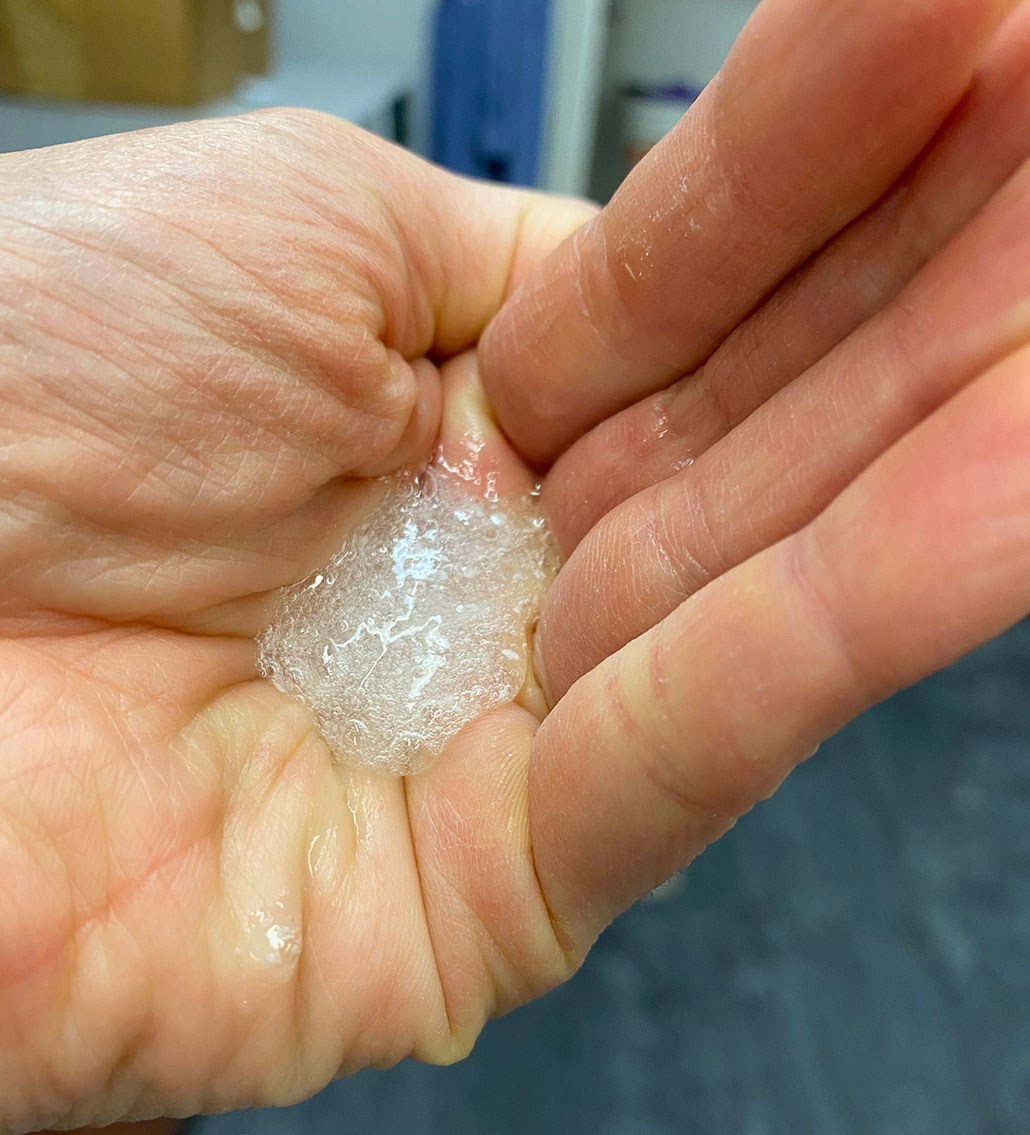 a photo of a person's hand holding a white bubbly goo that can produce electricity