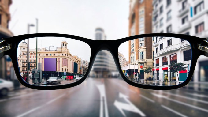 an illustration showing a photo of a city through glasses (in focus) and the city outside of the glasses (out of focus)