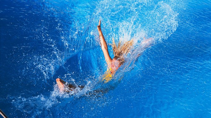 the moment a girl hits pool water after jumping in, the cavity her body makes and the beginning of her splash are visible