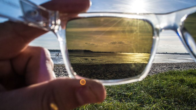 a photo of the view through polarized sunglasses at a beach looking towards the water and the sun