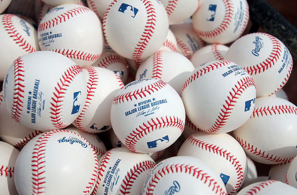 a pile of white baseballs with red stitching, the balls are stamped with 'Major League Baseball'