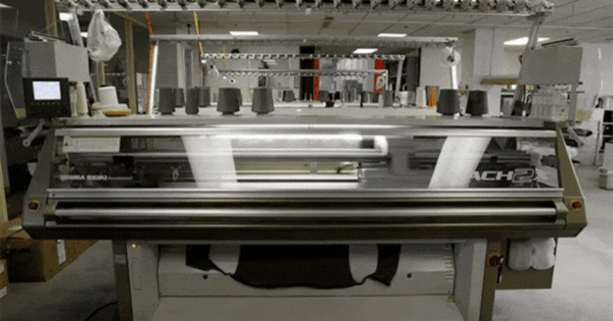 an animation showing a machine knitting a garment that falls onto the floor after being completed