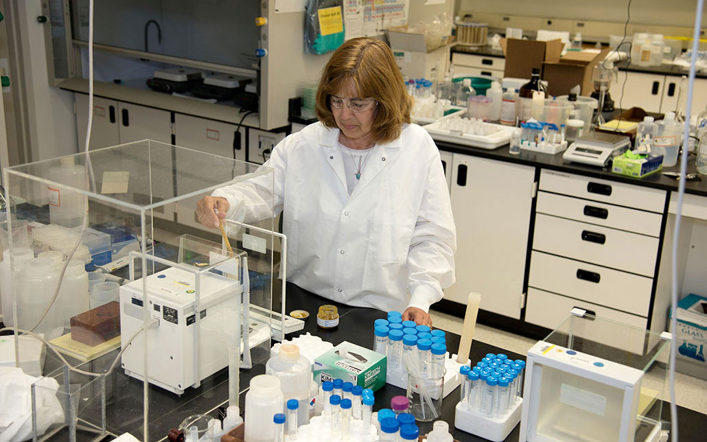 a woman wearing a lab coat is working with samples of baby food in a lab