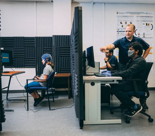 a photo showing a partition between the girl with the EEG cap and the researchers 