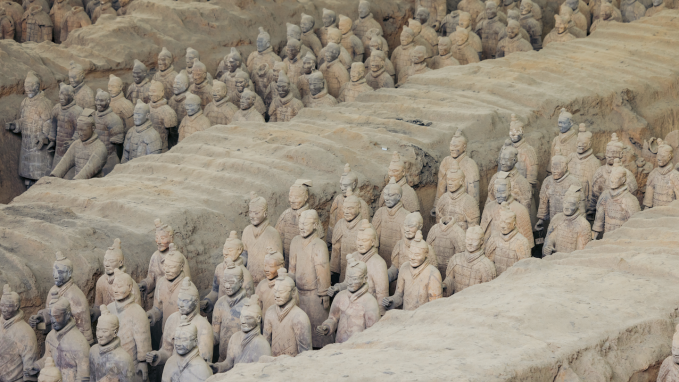 rows of terra cotta soldiers stand guard around a tomb